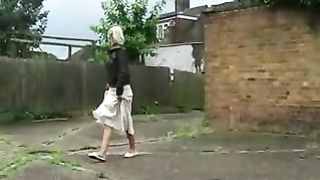 Sexy blonde pees behind a wall