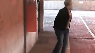 Mature woman peeing on a parking lot