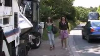Two girls peeing near a garbage truck