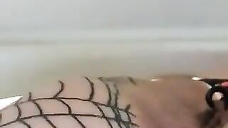 Girl in tight fishnet stockings stands over a shower drain