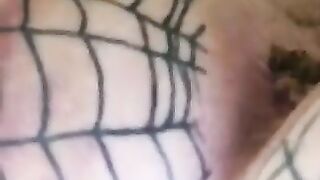 Woman covered in fishnet stockings squats on a pile of shit