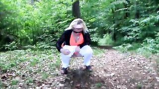 Mature lady poops in the forest next to the road