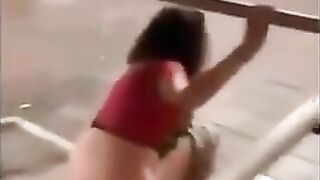 Girl pisses on floor while holding railing in a public place