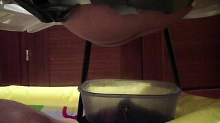 Woman crouches over bucket, pisses into it