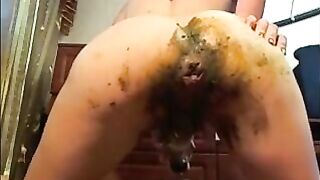 Woman shoves dildo in ass full of shit